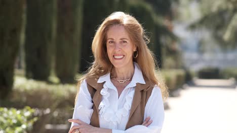 cheerful mature woman adjusting hair in city park