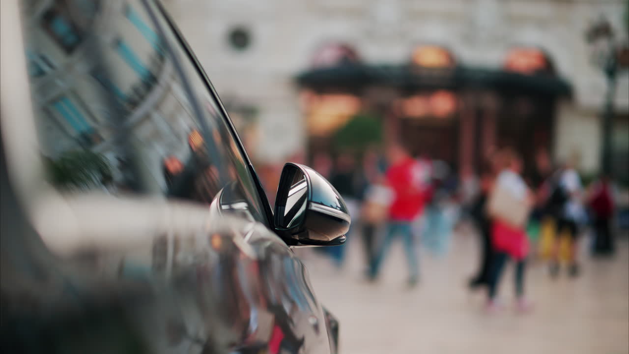 Black car parked in front of the Monta Carlo Casino with blurry people moving near it
