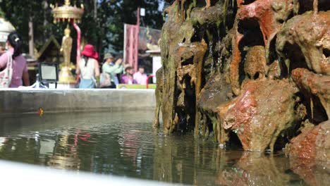 water cascading down a stone fountain, people in background