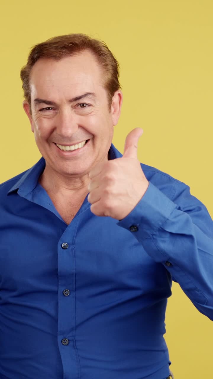Happy man giving thumbs up on yellow background