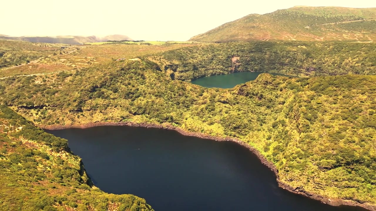 Vista aérea de lagos de cratera vulcânica cercados por colinas verdes exuberantes em Flores, Portugal.