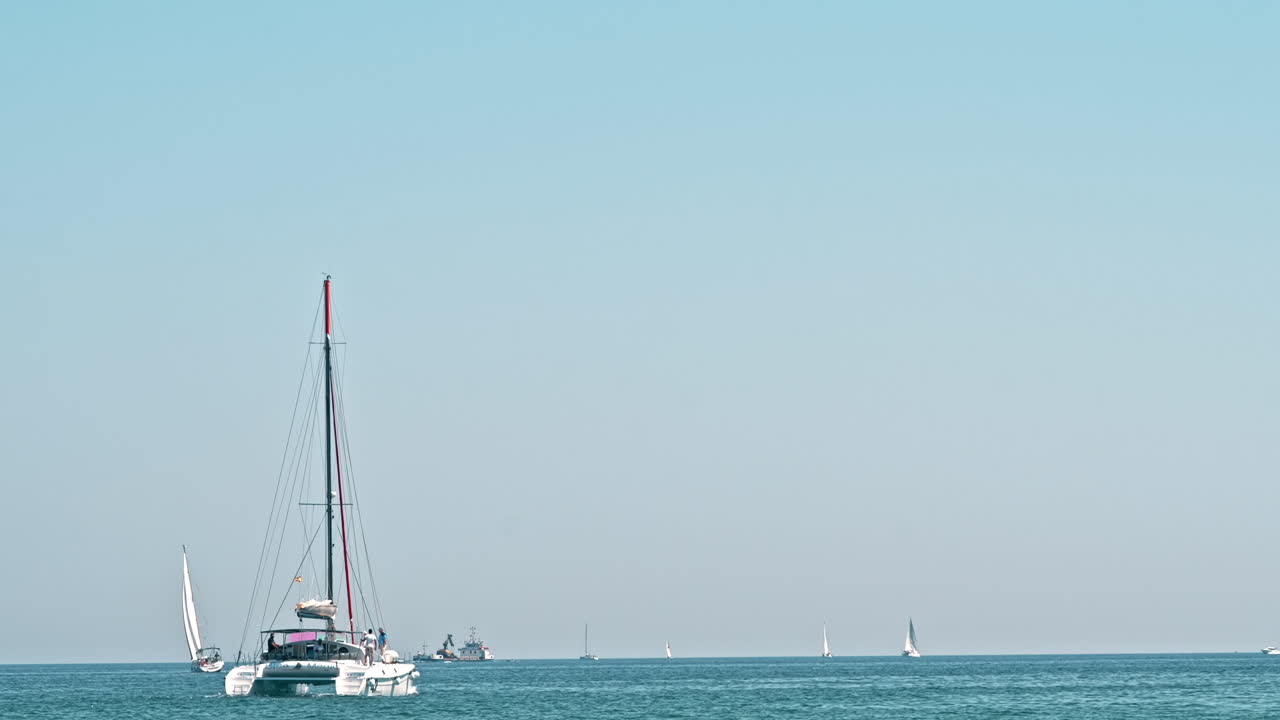 Floating boats and ship in the distance on Mediterranean sea coast in Barcelona, Spain