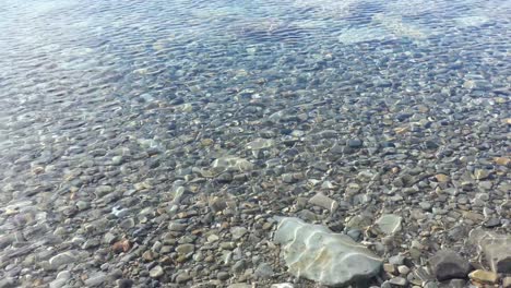 Langsamer-Spaziergang-Entlang-Des-Schönen,-Klaren-Wassers-Des-Alpensees-Mit-Einer-Vielzahl-Von-Steinen-Und-Farben