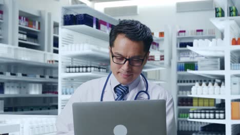 pharmacist working on laptop in pharmacy