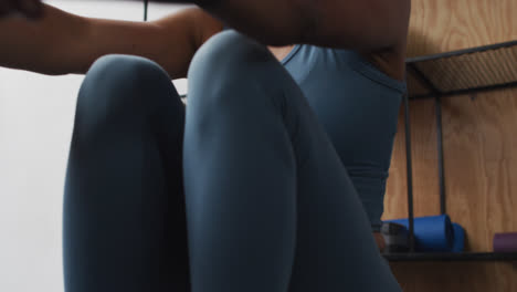 mixed race woman wearing face mask exercising at gym