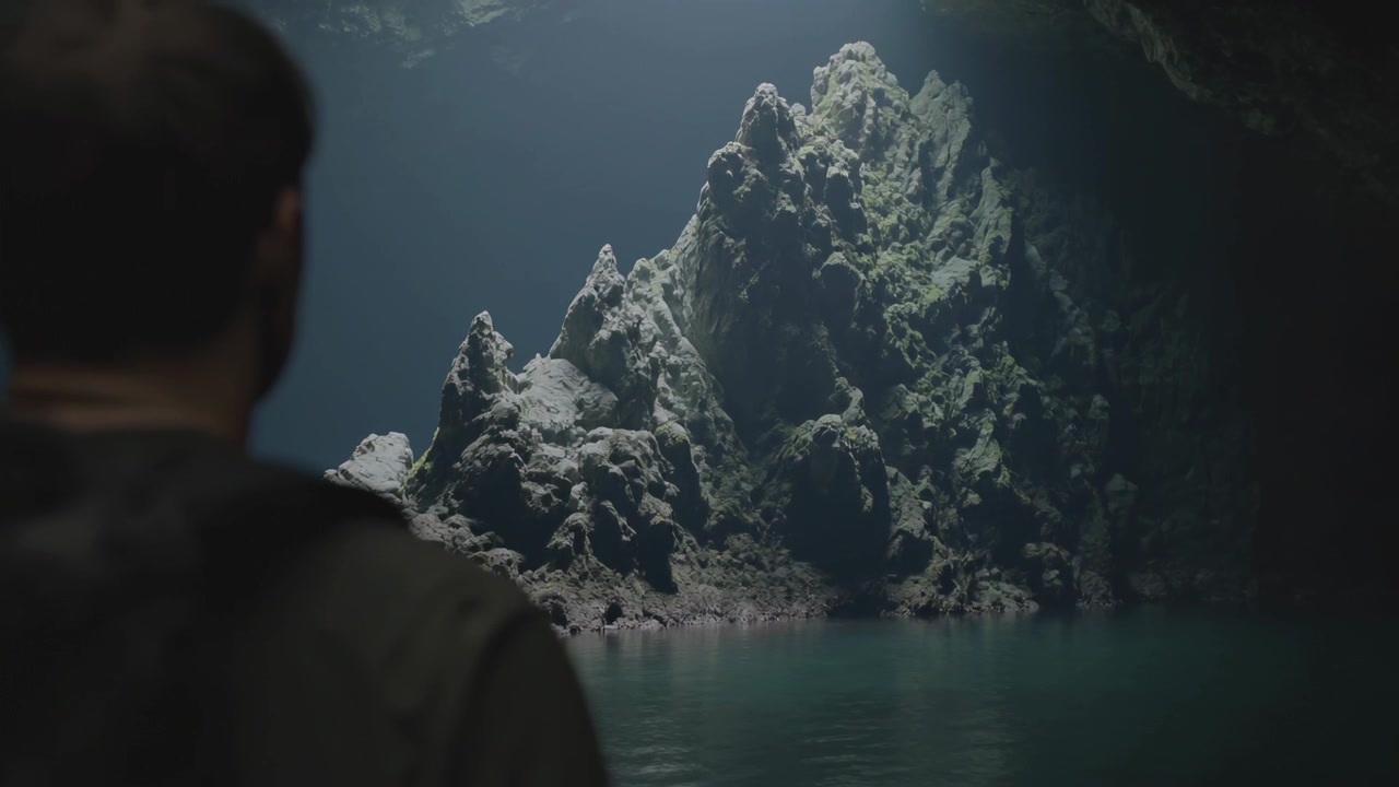 Entrando pela esquerda, homem se aproximando de um monte de rochas iluminado em uma piscina de caverna para observar a luz, usando uma jaqueta com capuz.