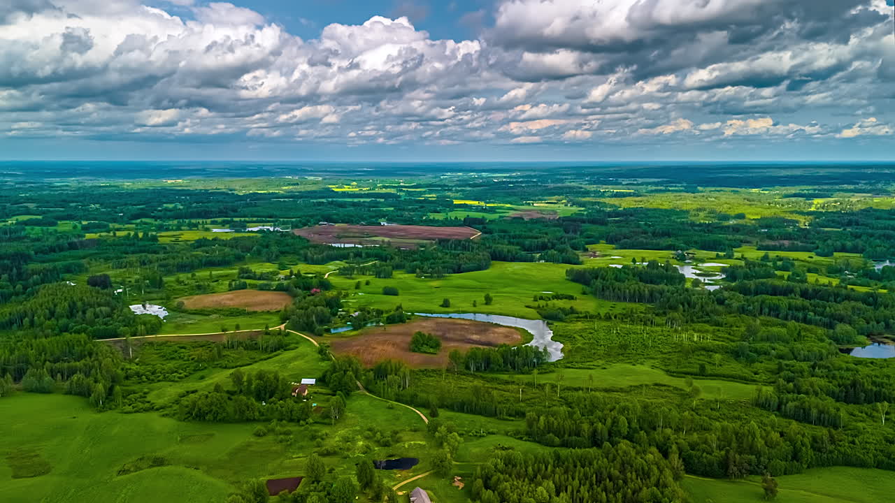 Breathtaking aerial clouds timelapse over vast, vibrant green landscape with rolling hills, dense forests, a meandering lakes, showcasing pristine nature and rural scenery of Latvian country