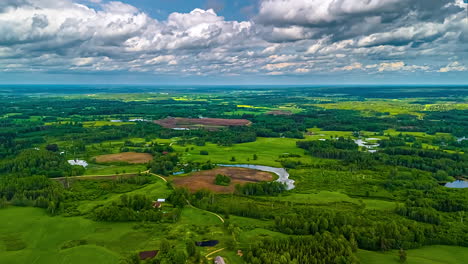 breathtaking aerial clouds timelapse over vast, vibrant green landscape with rolling hills, dense forests, a meandering lakes, showcasing pristine nature and rural scenery of latvian country