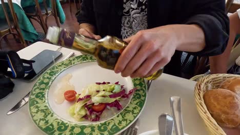 person adding dressing to a fresh salad