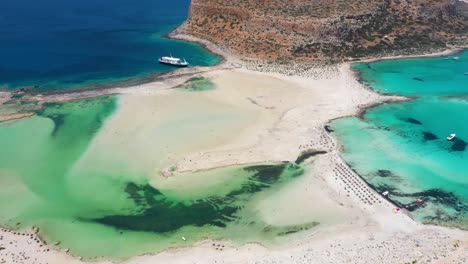 Vuelo-Aéreo-Sobre-La-Playa-De-Balos-Y-La-Laguna-Con-Agua-Turquesa,-Montañas-Y-Acantilados-En-Creta,-Grecia