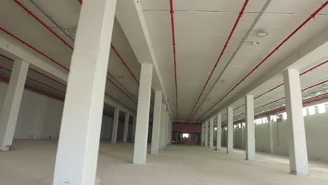 wide spaces with white symmetrical columns and red pipes on the ceiling