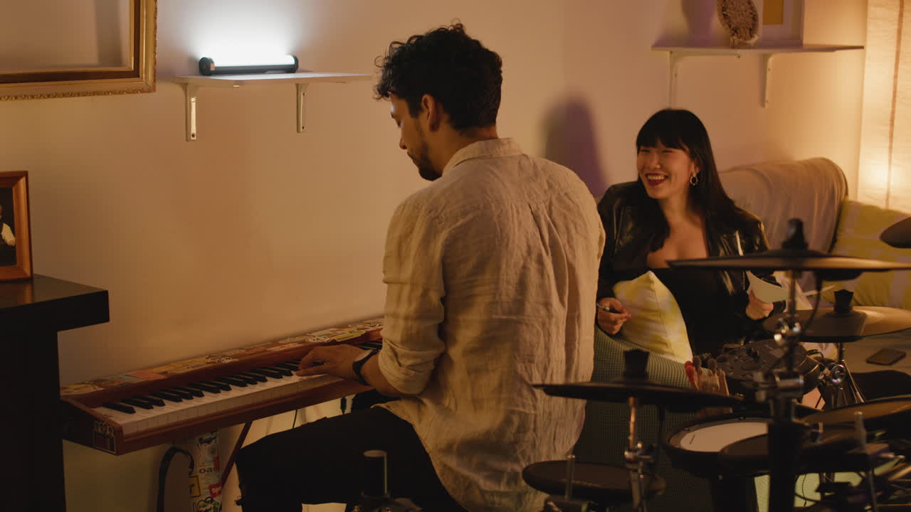 Man playing piano with woman nearby