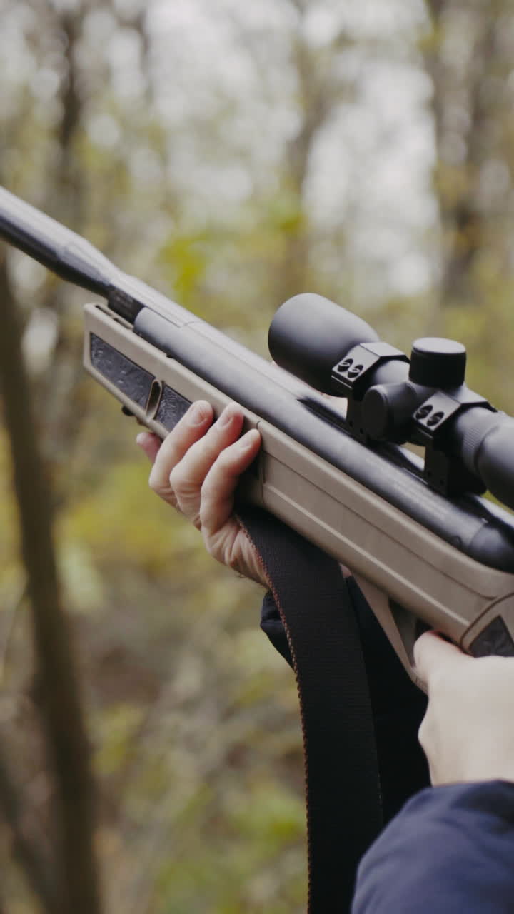 Hunter holding hunting rifle. Close up of young hunter holding hunting rifle aiming in forest