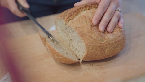 Hände-Schneiden-Frischen-Laib-Brot,-Nahaufnahme