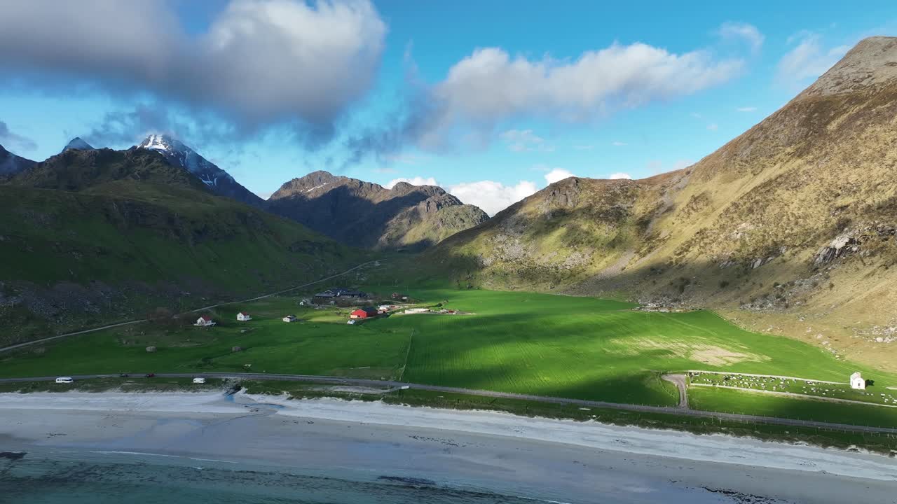 Drone pulls back from Haukland beach and starts revealing farmlands, ocean and mountains at sunset