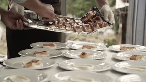 Hands-of-chef-put-freshly-cooked-salmon-into-plates,-close-up-view