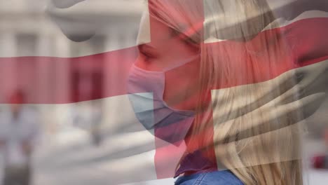 Animation-of-flag-of-switzerland-waving-over-caucasian-woman-wearing-face-mask-in-city-street