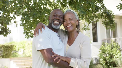 portrait of happy african american senior couple embracing in sunny garden, slow motion