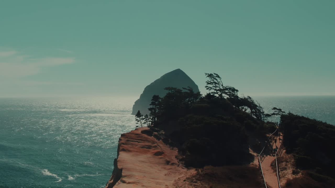 4k Aerial Big rock in Pacific ocean with rocky hill in foreground Drone truck right