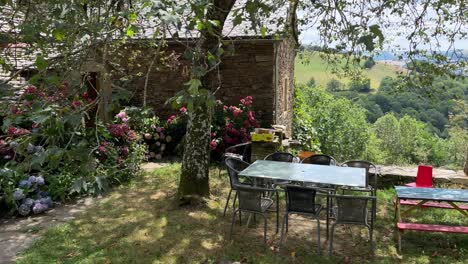 In-the-courtyard-of-the-stone-house-on-the-mountain,-filled-with-hydrangea-flowers,-there-are-tables-and-chairs-placed
