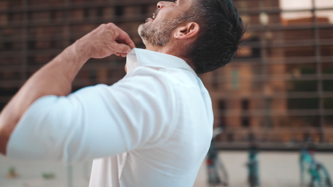 Man buttoning his white shirt outdoors