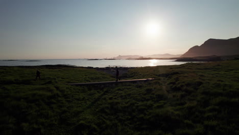 Hiker-walking-over-a-stone-bridge-with-a-scenic-landscape-and-cheep-enjoying-the-view-in-the-background