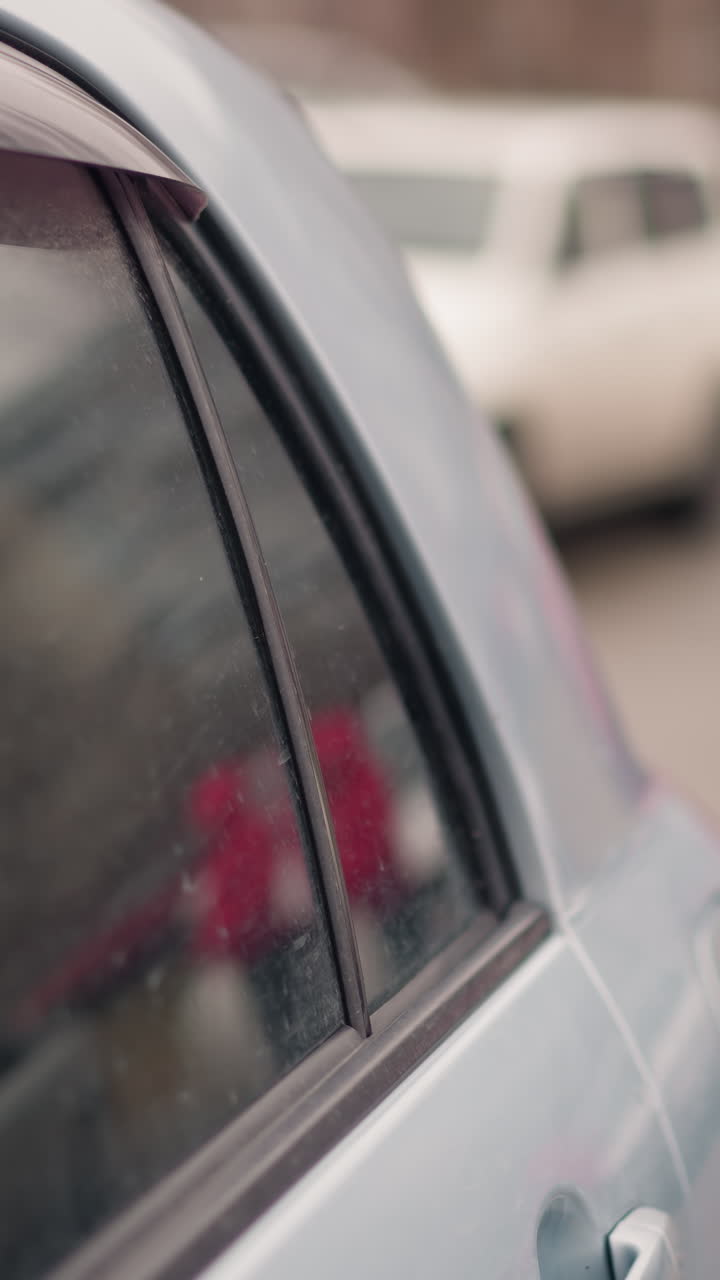 близкий вид припаркованных автомобилей с другой машиной, проходящей на заднем плане, фокус на боковом окне пепельной машины