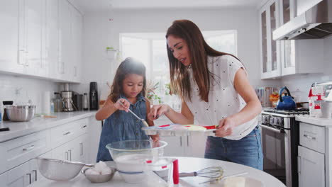 joven poniendo mezcla de pasteles en formas de pastel mientras hornea con su madre en la cocina, cerca