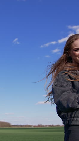 Female soloist sings into the microphone. Beautiful happy woman singing and moving her head while dancing in a green field. Energetic music and dancing. Vertical video