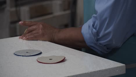 craftsman changing polishing pads on his rotary polisher whilst grinding a granite counter top.