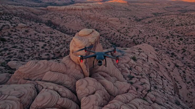 Aerial video captures a drone flying over a rugged desert landscape at sunset, showcasing stunning