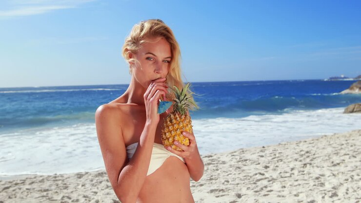 Attractive blonde drinking cocktail in pineapple