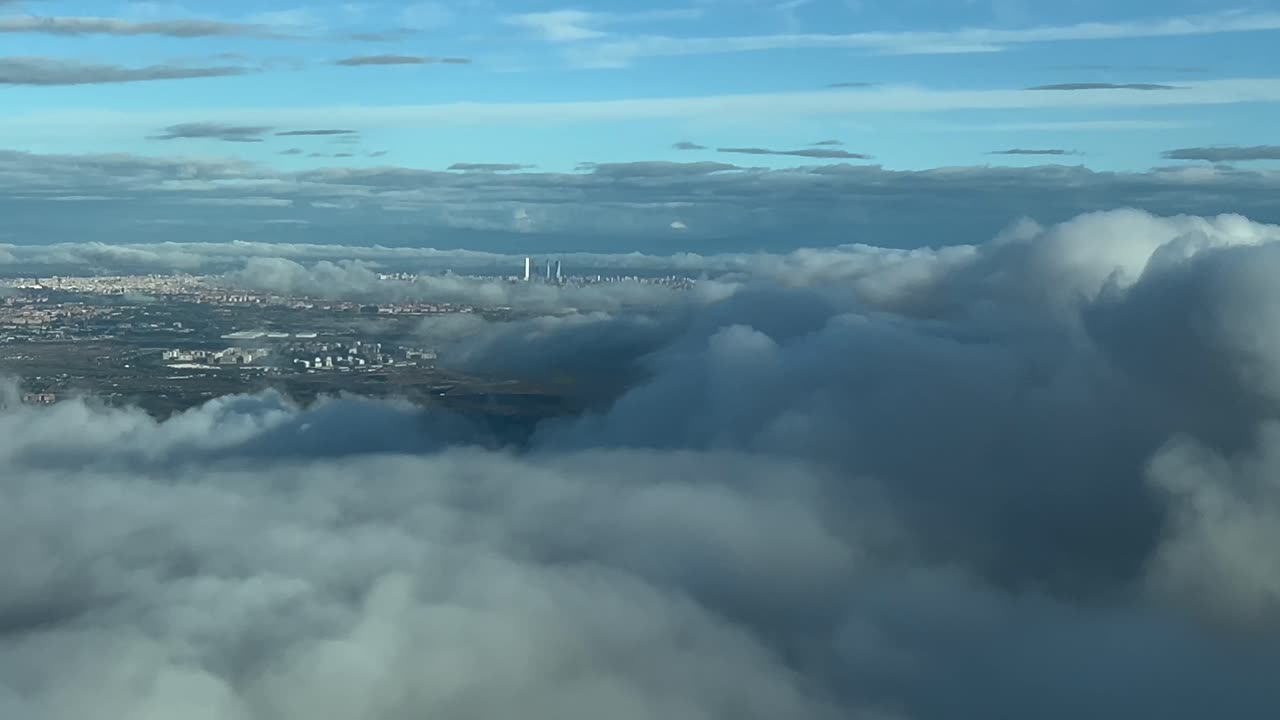 vista aérea de la ciudad de madrid, españa, tomada desde una cabina de un avión que vuela sobre algunas nubes que se acercan al aeropuerto