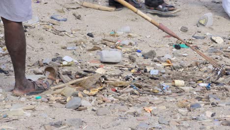 man-collecting-waste-plastic-with-rake-agriculture-tool-in-Carter-road-beach-mumbai-india-closeup-shot