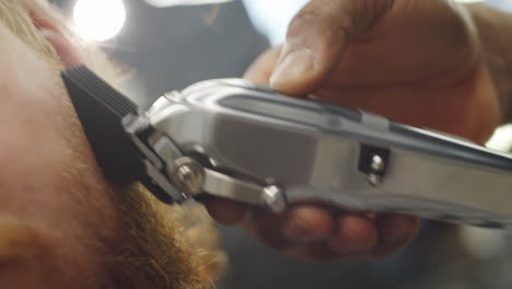 trimming beard with hair clippers in barbershop