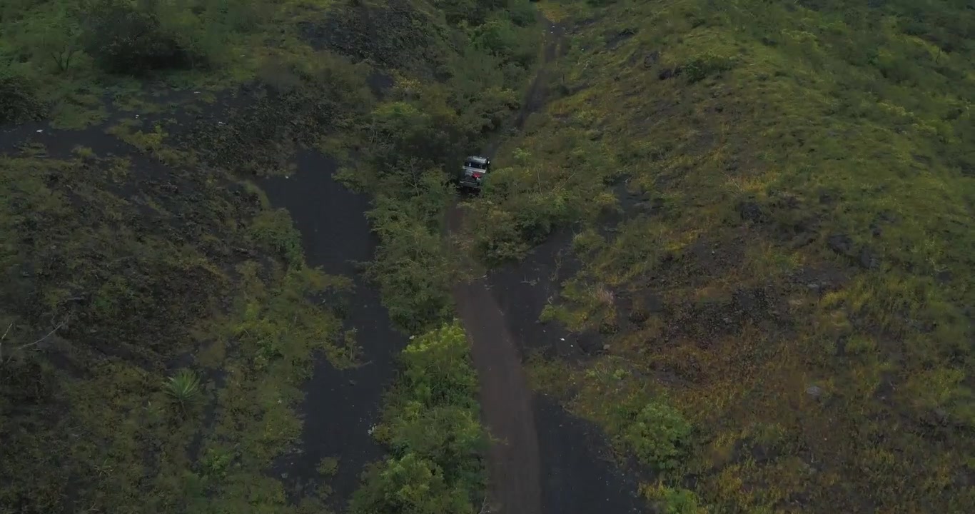 Ripresa aerea con drone di auto che guidano fuoristrada in una foresta, rivelando paesaggi e montagne, durante un viaggio in campeggio verso il vulcano Pacaya, Guatemala
