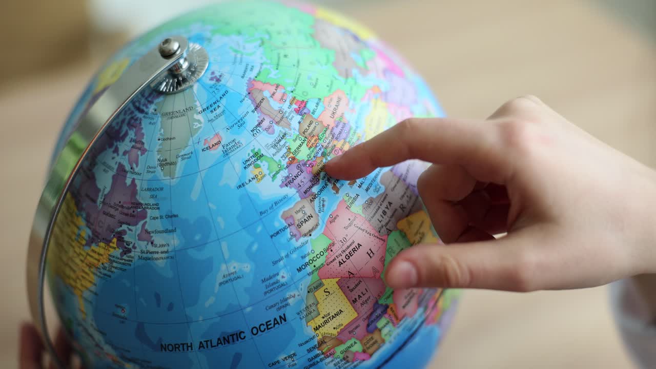 Finger pointing at a globe showing Europe and the North Atlantic Ocean
