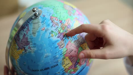 finger pointing at a globe showing europe and the north atlantic ocean