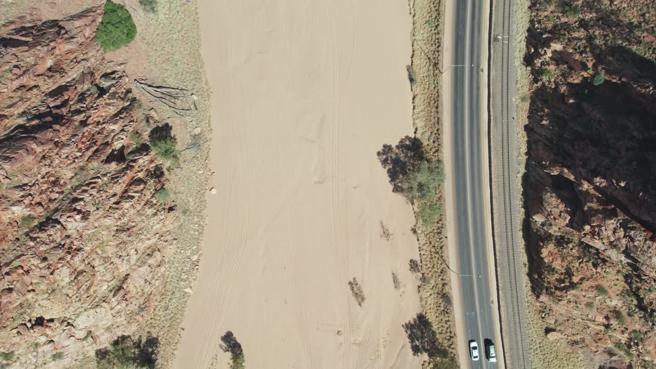 Static drone view looking straight down on the dry Todd RIver and the Stuart Highway at Heavitree Gap in Alice Springs, Mparntwe. Northern Territory, Australia. August 2022.