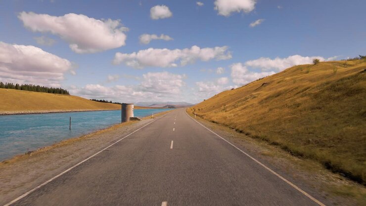 Guida soleggiata lungo una strada accanto a un canale idroelettrico artificiale a Canterbury, Nuova Zelanda