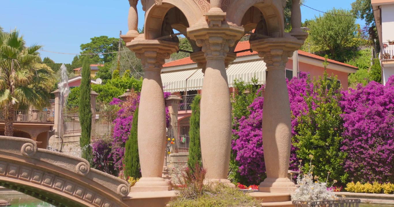 Ponte e colonne in pietra ornati nel Giardino di Villa Grock a Imperia, Italia. - Inquadratura dal basso verso l'alto