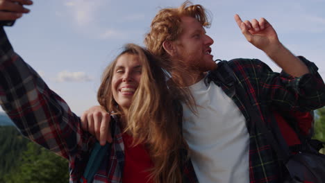 mujer y hombre felices hablando en video por teléfono móvil durante una caminata en las montañas