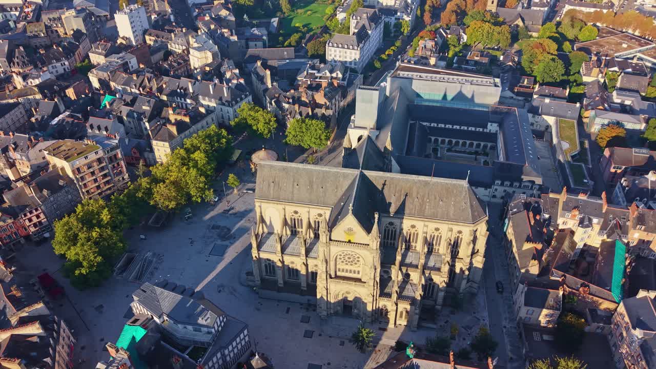 Orbiting drone view of Sainte-Anne Church at sunrise, with the Jacobins Convent behind, showing the square, surrounding streets, rooftops, trees and morning light - Rennes Brittany