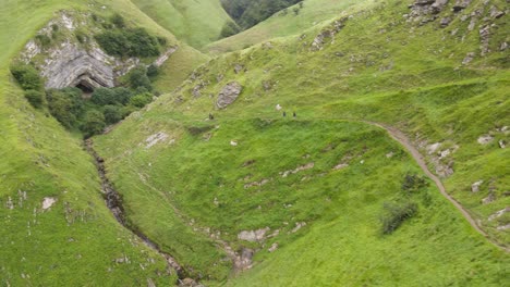 People-on-the-fresh-green-pathway-walking-toward-the-mouth-of-the-Arpea-Cave