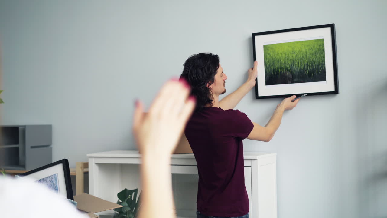 una pareja colgando un cuadro.