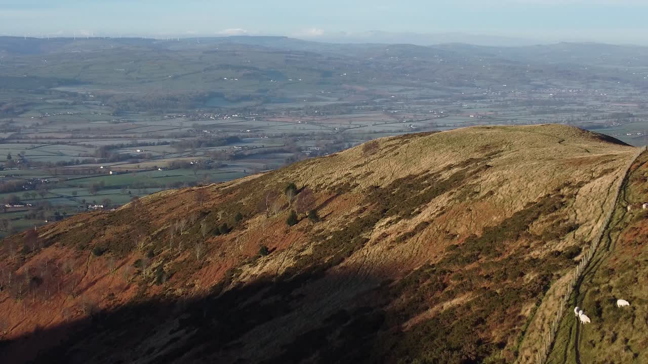 la primera luz del sol en el pico de la montaña de las tierras altas vista aérea a través del vasto campo de tierras de cultivo idílico y helado crece lentamente
