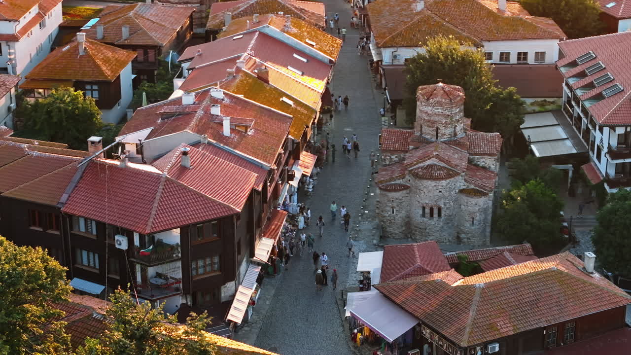 Aerial drone view of people moving through the old town Nessebar, Bulgaria at sunset