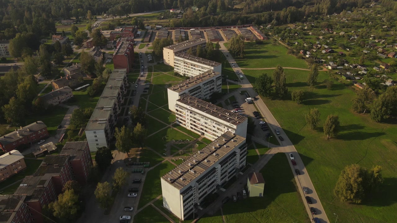 Widok z drona na małe miasteczko Liepa, skąpane w pięknym świetle dziennym. Scena przedstawia budynki, ulice i otaczającą zieleń w spokojnym wiejskim krajobrazie.