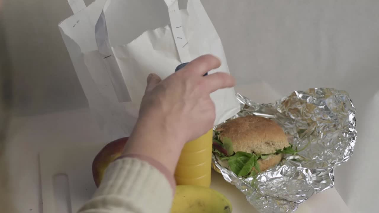 Packing a healthy lunch with sandwich and orange juice into a bag overhead shot