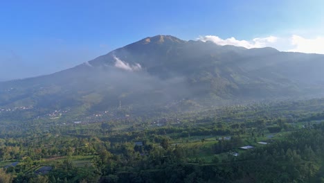 aerial view of indonesian tropical rural landscape in foggy morning with mount merbabu on the background. 4k drone footage.